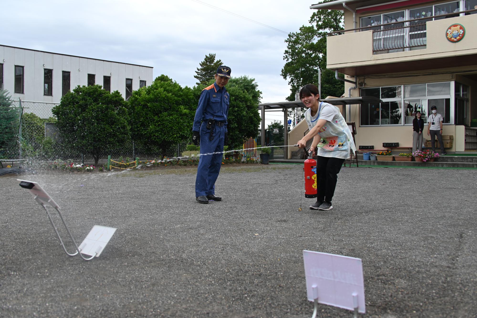 水消火器訓練をする幼稚園の先生